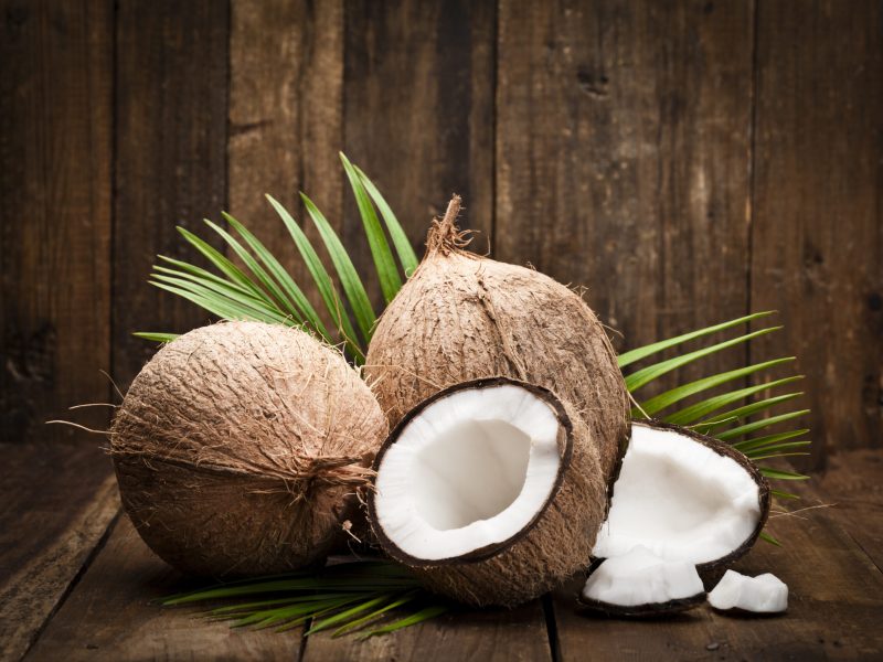 Two whole coconuts, an open coconut and coconut pieces shot on rustic wood table. DSRL studio photo taken with Canon EOS 5D Mk II and Canon EF 100mm f/2.8L Macro IS USM